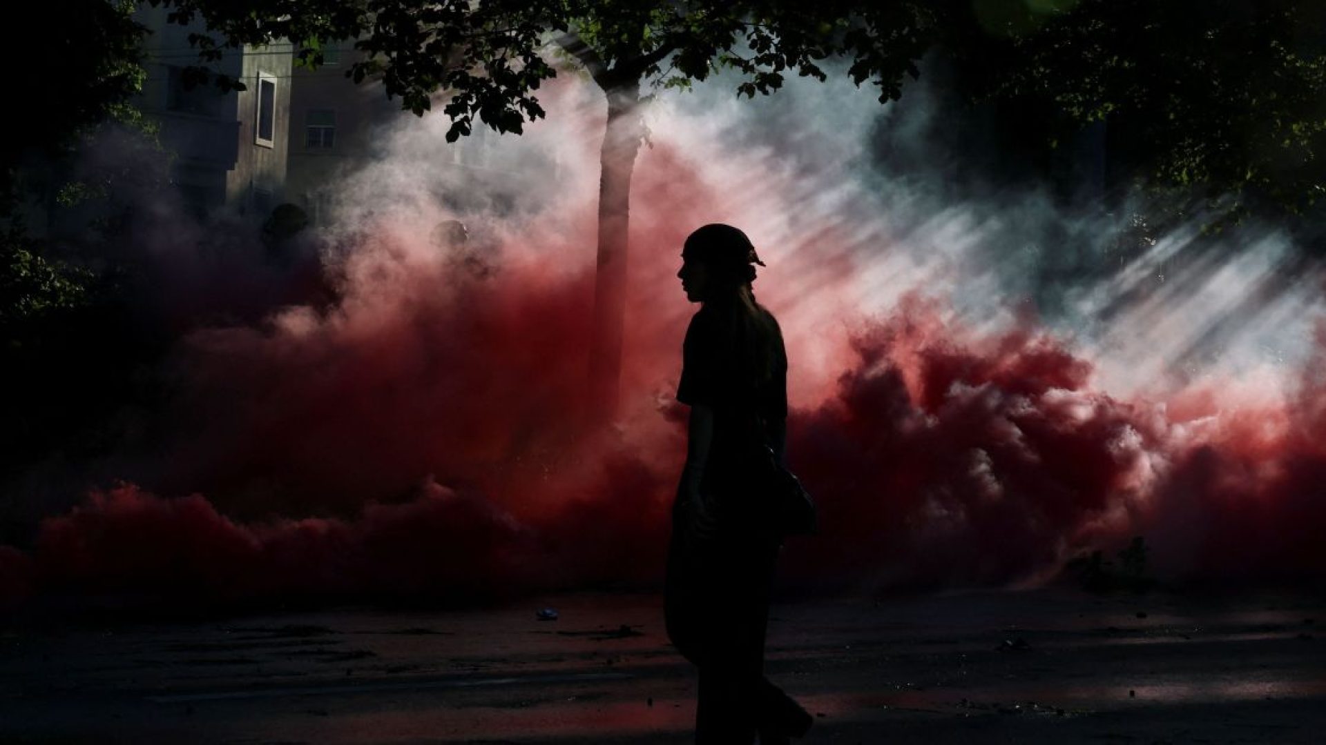 Pessoa caminha em meio a nuvens de fumaça durante protesto em Genebra contra a próxima cúpula do G7 em 14 de junho de 2026  • Denis Balibouse/Reuters