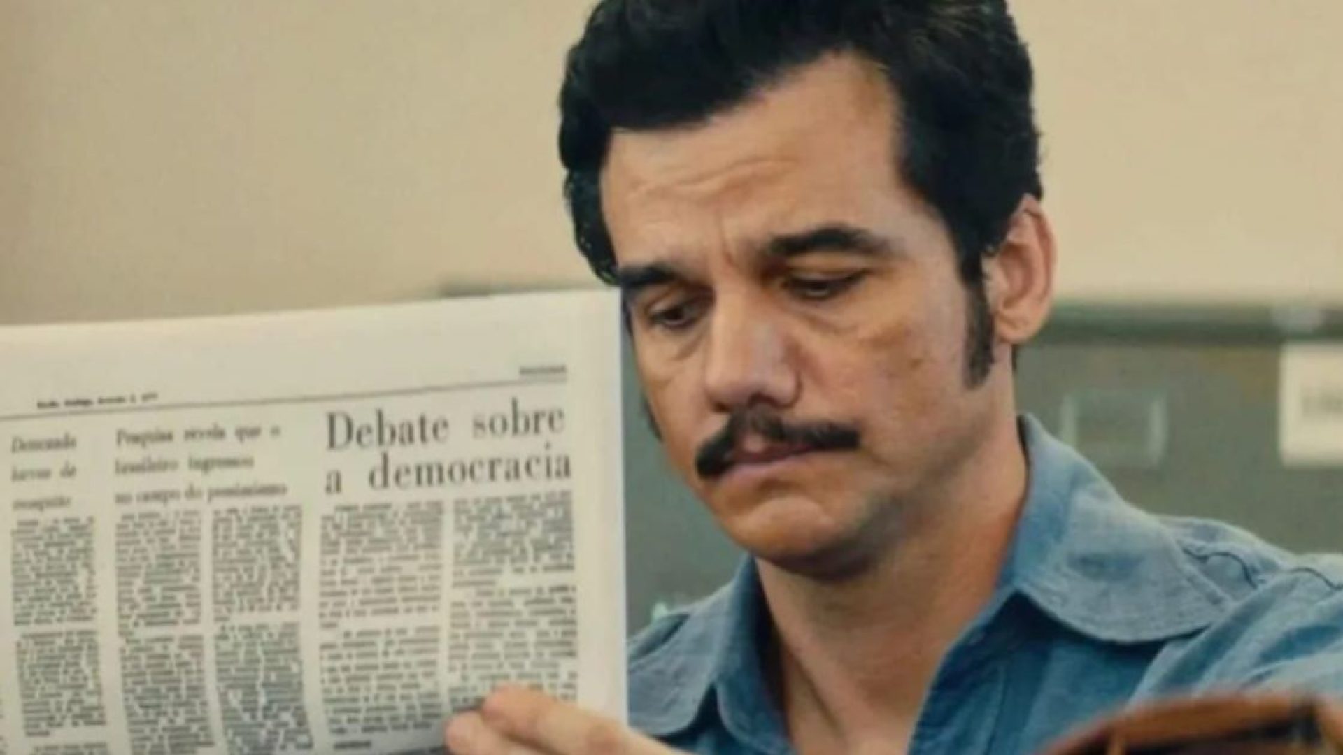 Marcelo (Wagner Moura) lê jornal no instituto de identificação, em "O Agente Secreto"  • Reprodução