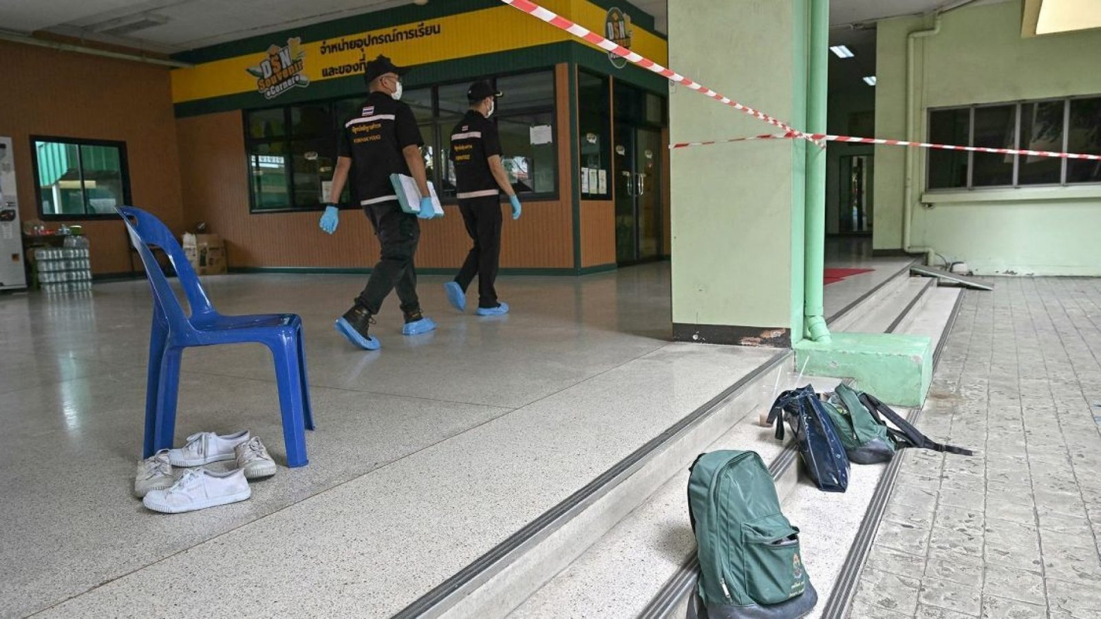 Pertences de alunos são vistos no local do tiroteio na escola enquanto policiais da perícia passam pelo local  • Lillian Suwanrumpha/AFP/Getty Images via CNN Newsource
